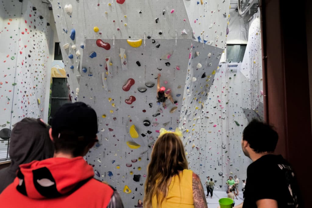 Mesa Rim inspires a safe, non competitive community that helps members to grow and cheer each other on. Here you can see members watching and supporting the climber ahead successfully (Halloween costume and all!) lead climb his way up the wall. 